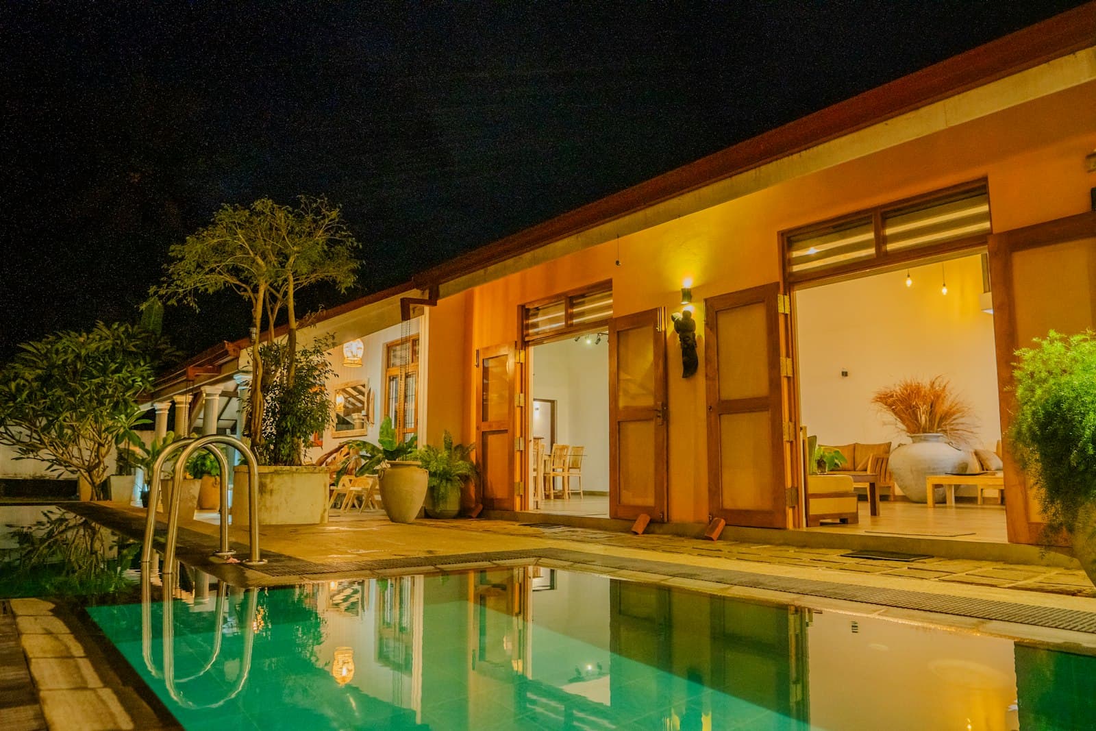 Tropical villa lit at night beside a still pool